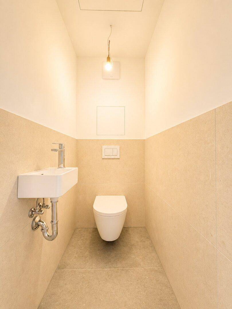 Modernes Gäste-WC mit wandhängender Toilette und kleinem Waschbecken.