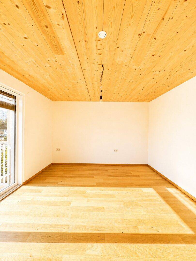 Geräumiger, heller Raum mit Holzboden und Holzdecke, ideal für Schlafzimmer oder Büro.