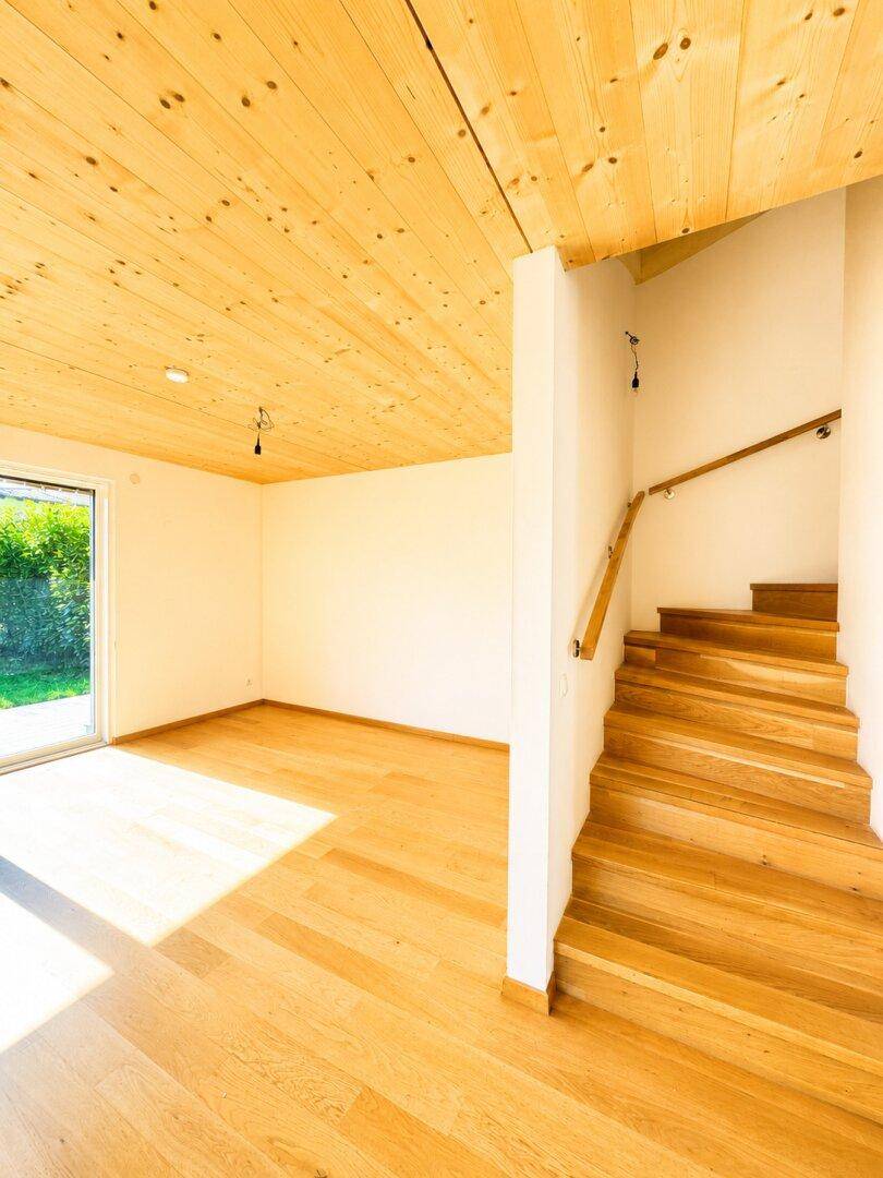 Geräumiger Raum mit Holzdecke, Holzboden und offener Holztreppe, sehr hell.