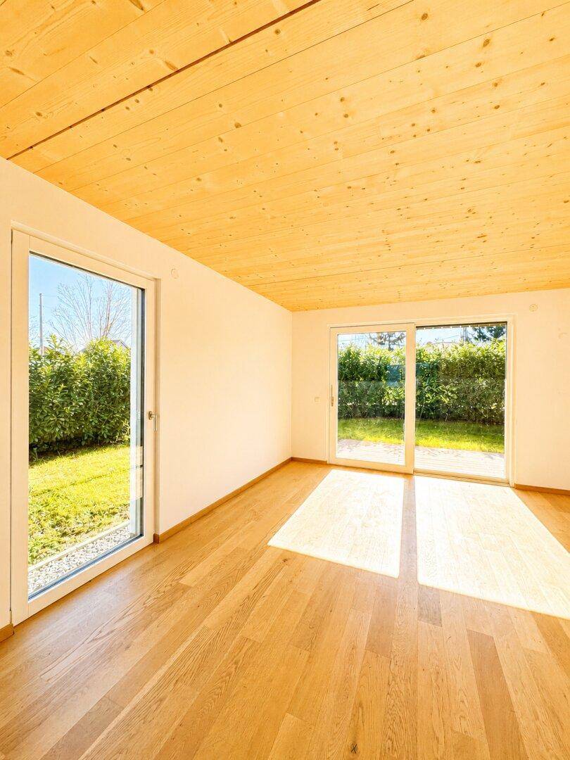 Heller Raum mit Holzboden, Holzdecke und Zugang zum Garten, lichtdurchflutet.