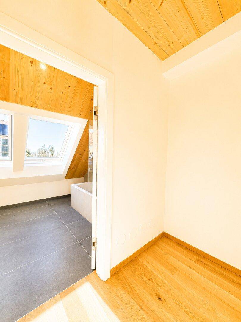 Heller Flur mit Holzboden, der zu einem modernen Badezimmer mit Dachfenstern führt.