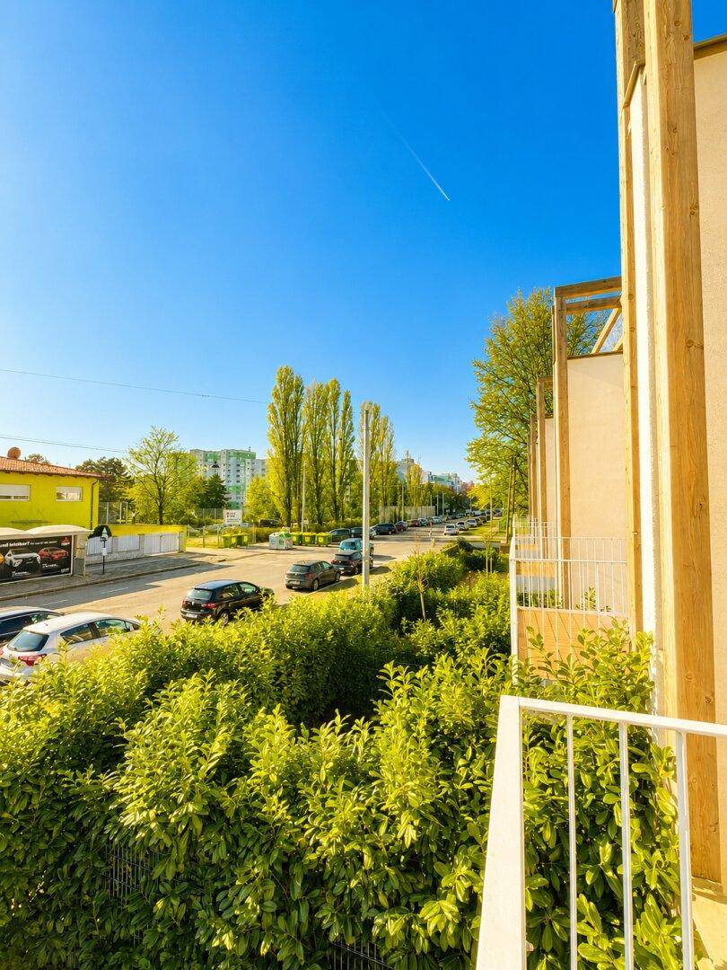 Balkon mit Blick auf die Straße und umliegende Gebäude an einem klaren, sonnigen Tag.