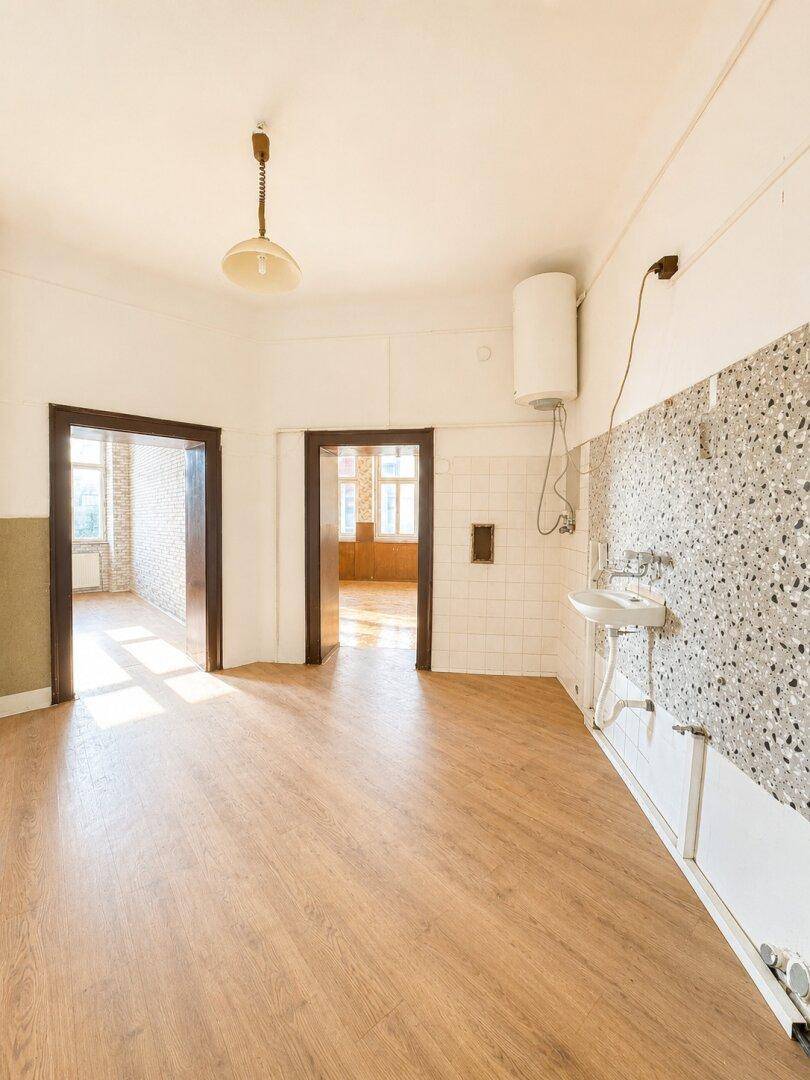 Leere Küche mit Spülbecken, Boiler und Terrazzo-Fliesen an der Wand.