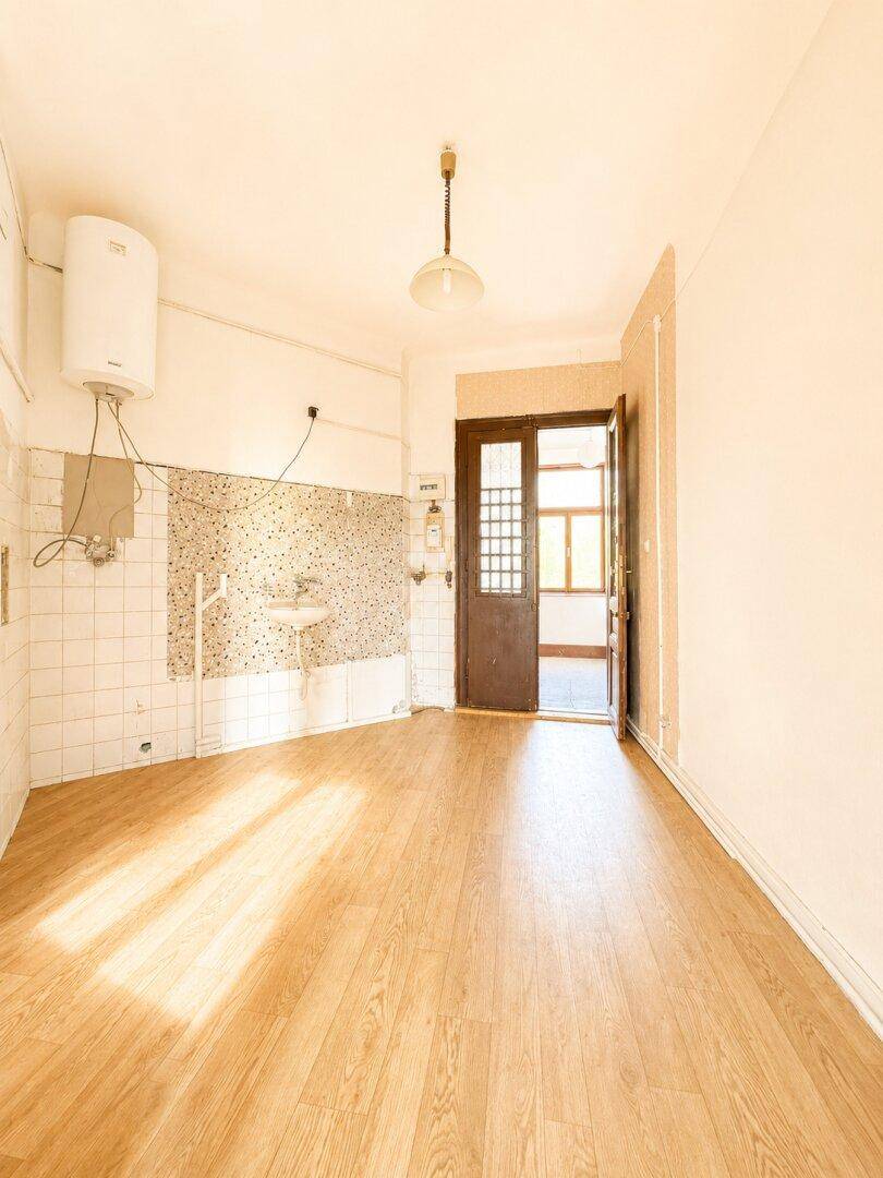 Helle Küche mit Spülbecken, Boiler und Terrazzo-Fliesen an der Wand.