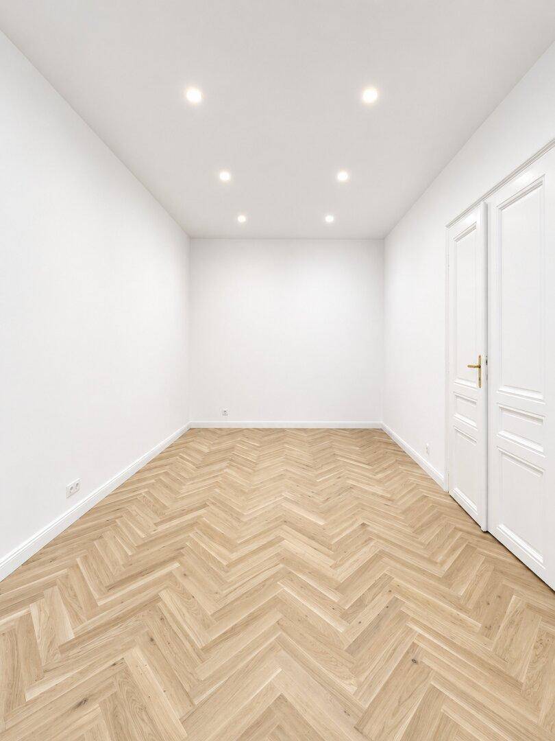 Schlichtes, helles Zimmer mit Fischgrätparkett und hohen Decken, ideal für vielfältige Nutzung.