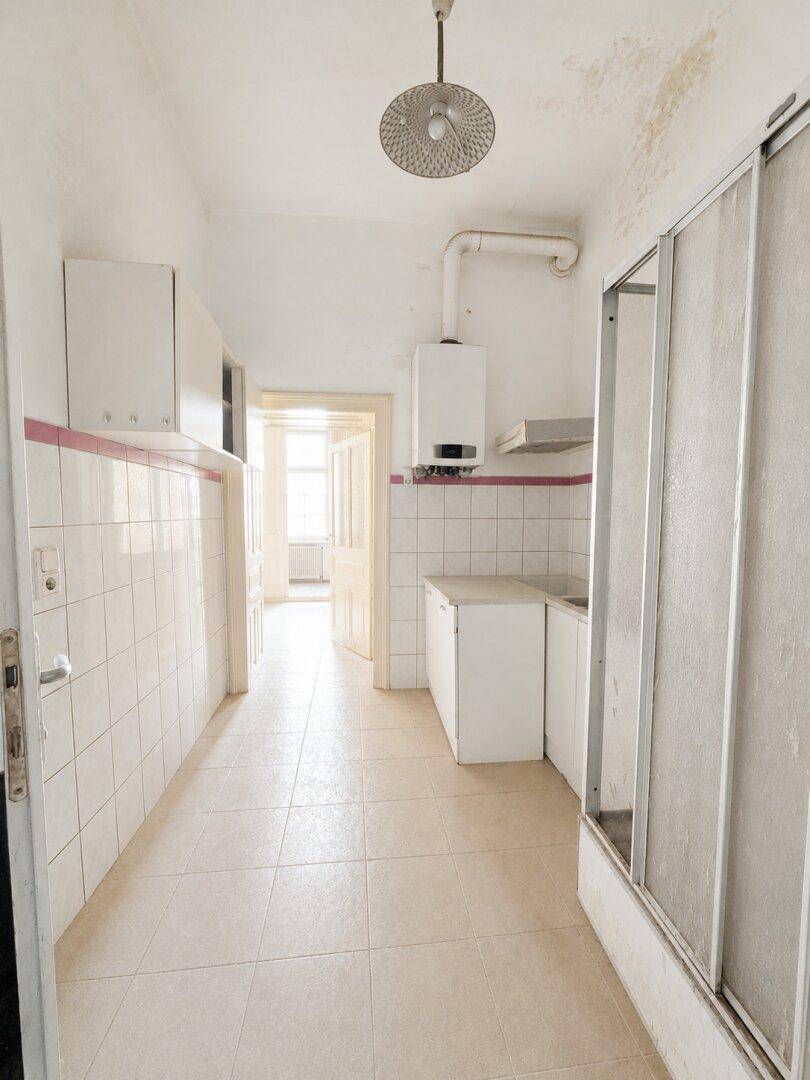 Alte Küche mit Fliesen, Gastherme und Spülbecken, zeigt deutliche Spuren von Wasserschäden an der Decke.