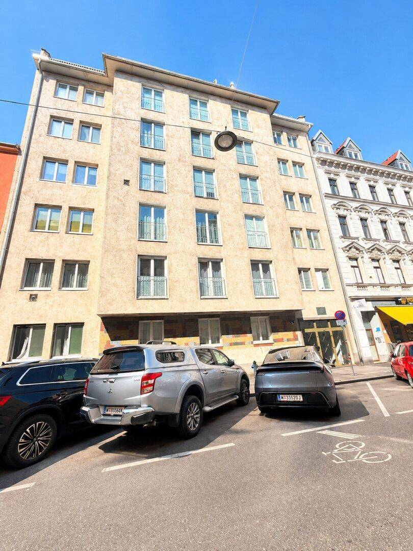 Mehrstöckiges Wohngebäude mit zahlreichen Fenstern und Balkonen an einer städtischen Straße.