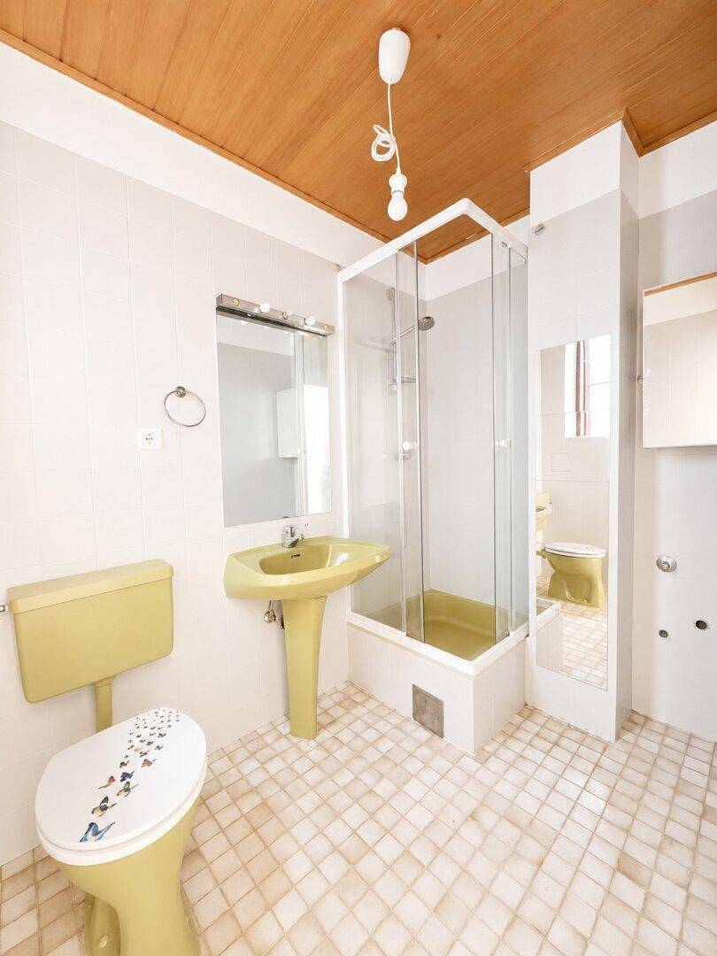 Badezimmer im 80er-Jahre-Stil mit gelben Sanitärobjekten, Dusche und Holzdecke.