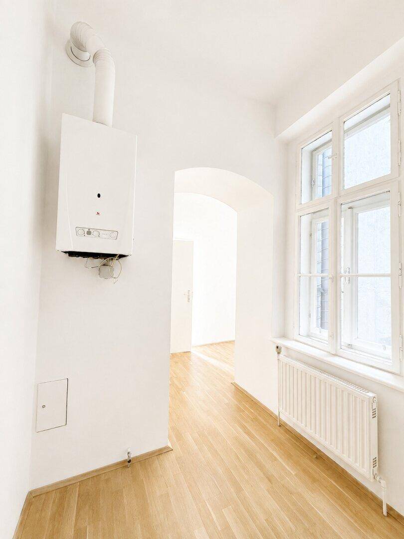 Heller Flur mit Gastherme und Fenster, der zu weiteren Räumen führt.
