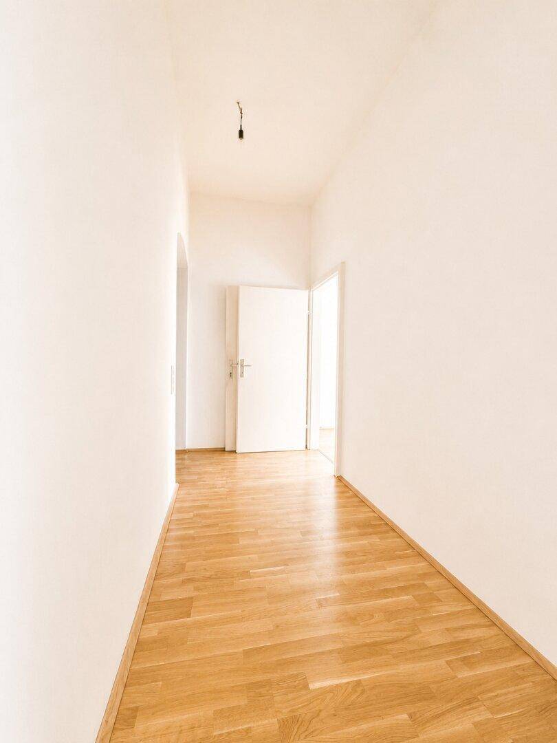Langer, heller Flur mit Parkettboden und Türen zu verschiedenen Zimmern.