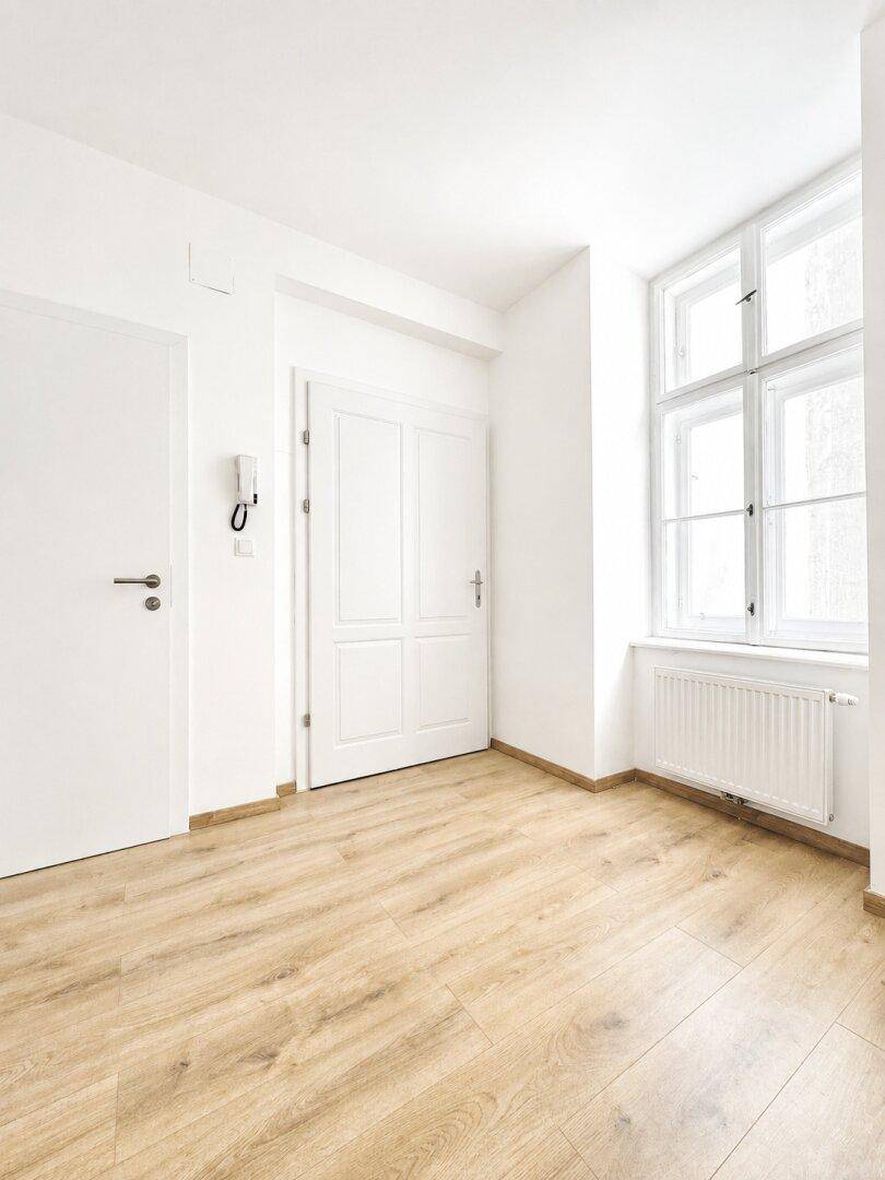 Eingangsbereich mit Laminatboden, weißen Türen und einem Fenster.
