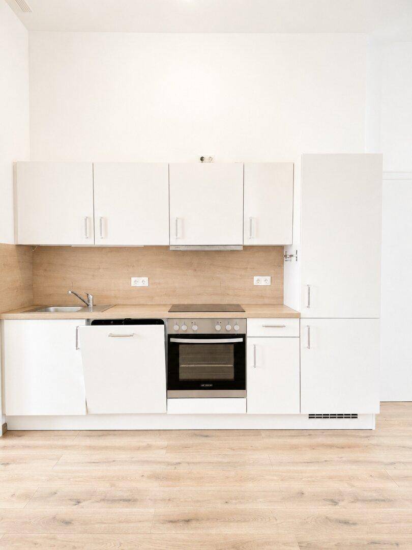 Moderne Einbauküche mit weißen Schränken, Holzoptik-Arbeitsplatte und integriertem Backofen.
