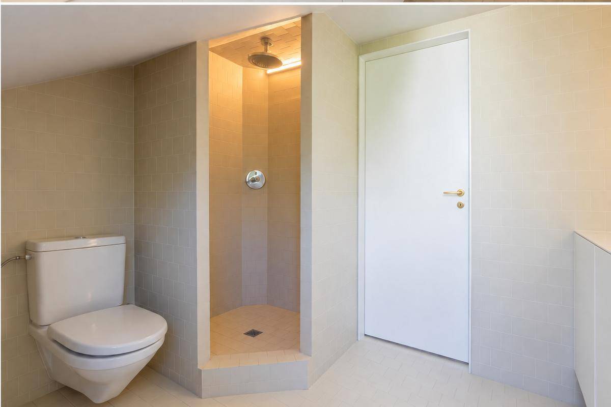 Funktionales Badezimmer mit WC und einer modernen begehbaren Dusche.