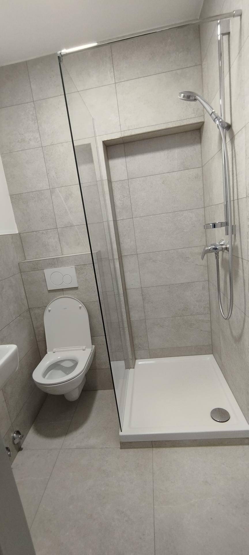 Modernes Badezimmer mit wandhängendem WC und einer Duschkabine mit Glasabtrennung.