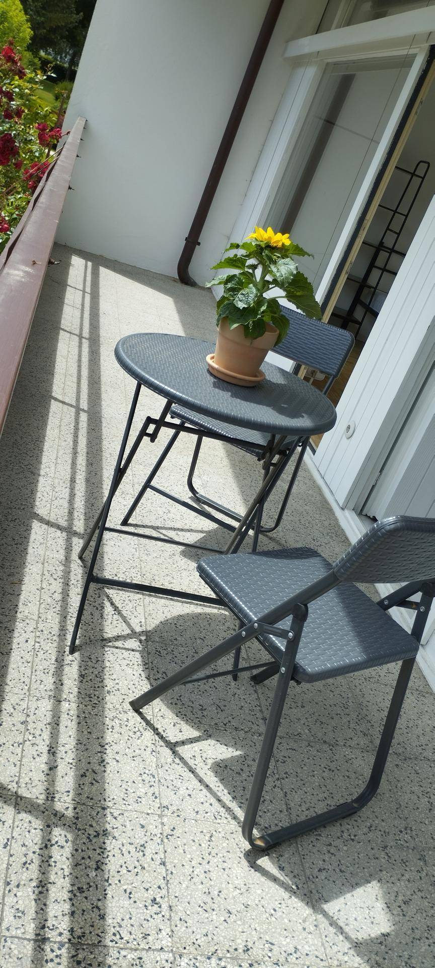 Balkon mit einem kleinen Tisch und zwei Stühlen, ideal für entspannte Stunden im Freien mit Blick ins Grüne.