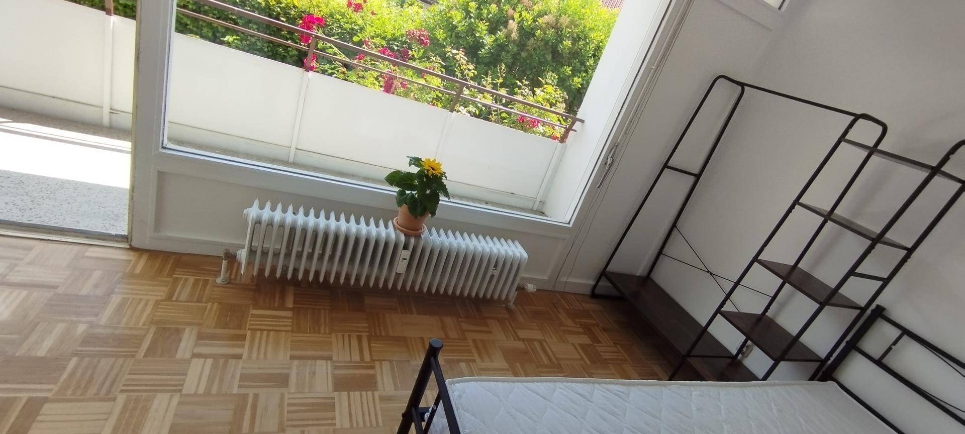 Schlafzimmer mit Parkettboden, einem einfachen Regal und direktem Zugang zum Balkon.