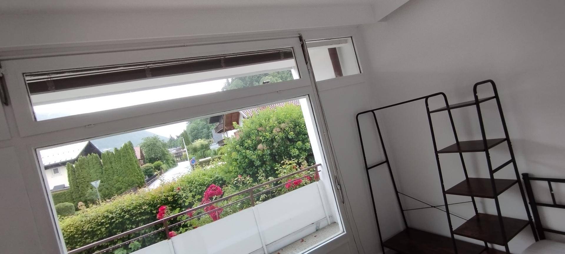 Schlafzimmer mit großem Fenster, das viel Tageslicht hereinlässt und einen Blick ins Grüne bietet.