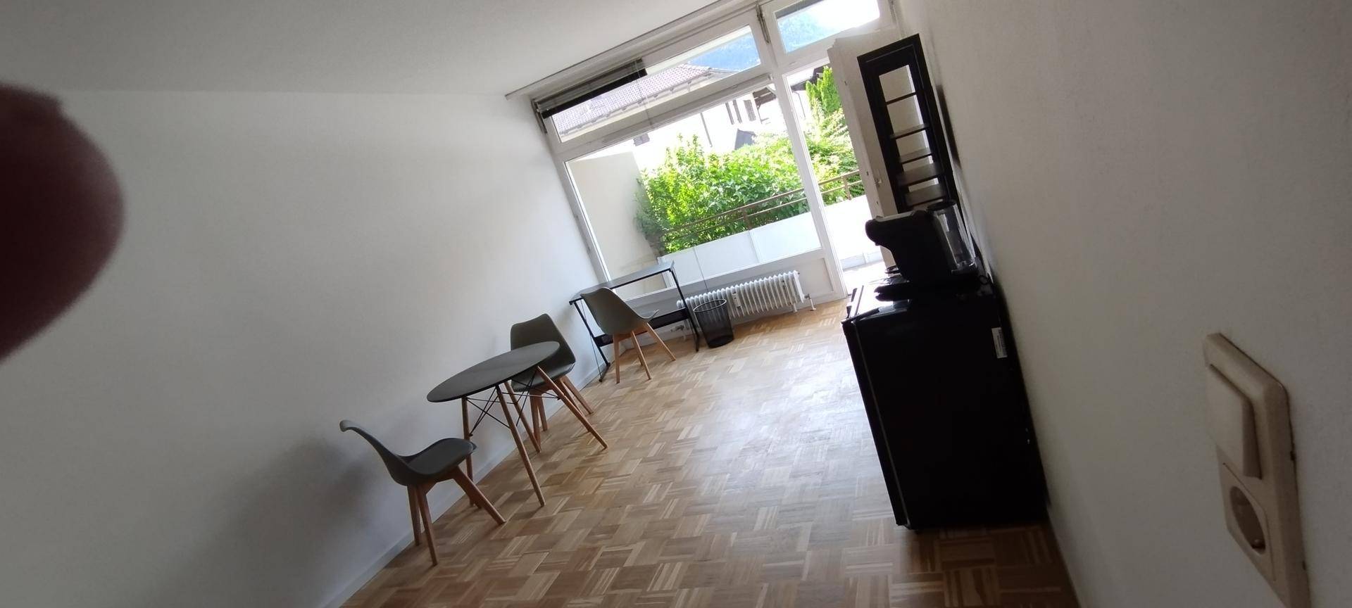Heller Wohnbereich mit Parkettboden, Esstisch und Zugang zum Balkon.
