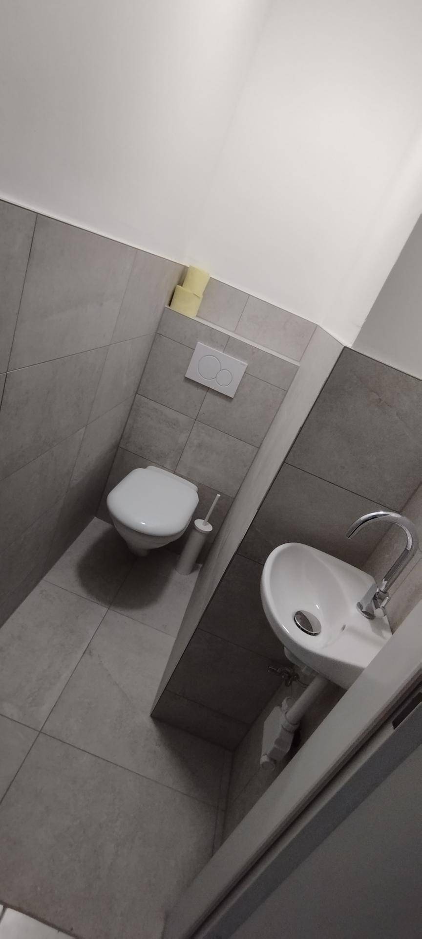 Modernes Gäste-WC mit grauen Fliesen und wandhängendem WC.