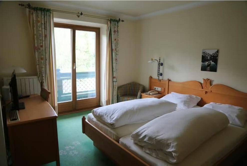 Komfortables Schlafzimmer mit zwei Einzelbetten, einem Schreibtisch und einem Fenster mit Blick ins Grüne.
