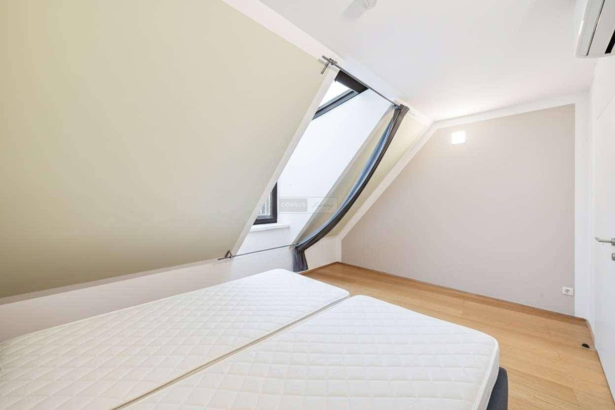 Helles Schlafzimmer mit Dachschrägen, Holzboden und einem großen Dachfenster für viel Licht.