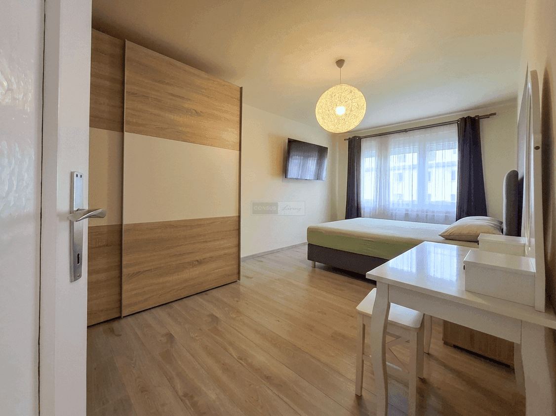 Geräumiges Schlafzimmer mit Doppelbett, großem Schiebetürenschrank und Schminktisch.