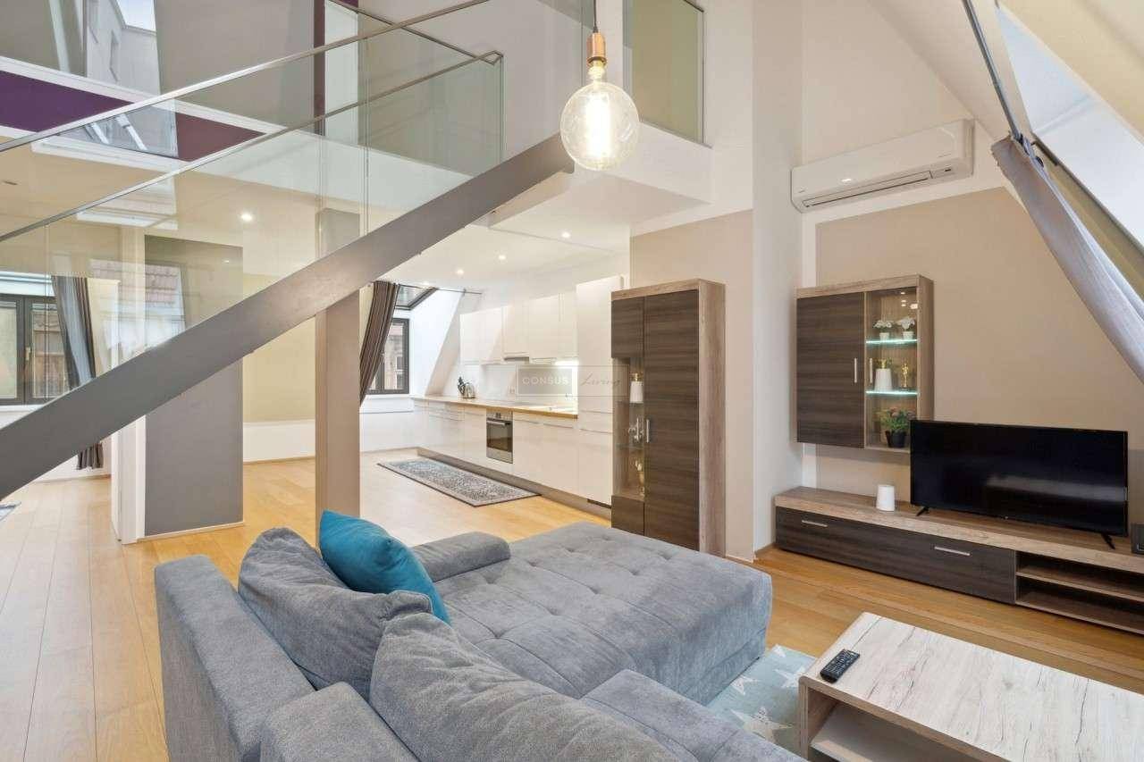 Moderner Wohnbereich mit Sofa, Fernseher und Blick auf die offene Küche im Hintergrund.