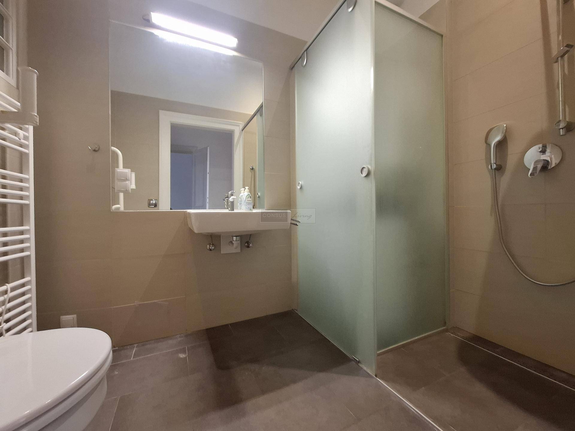 Modernes Badezimmer mit ebenerdiger Dusche, Einzelwaschbecken und beheiztem Handtuchhalter.