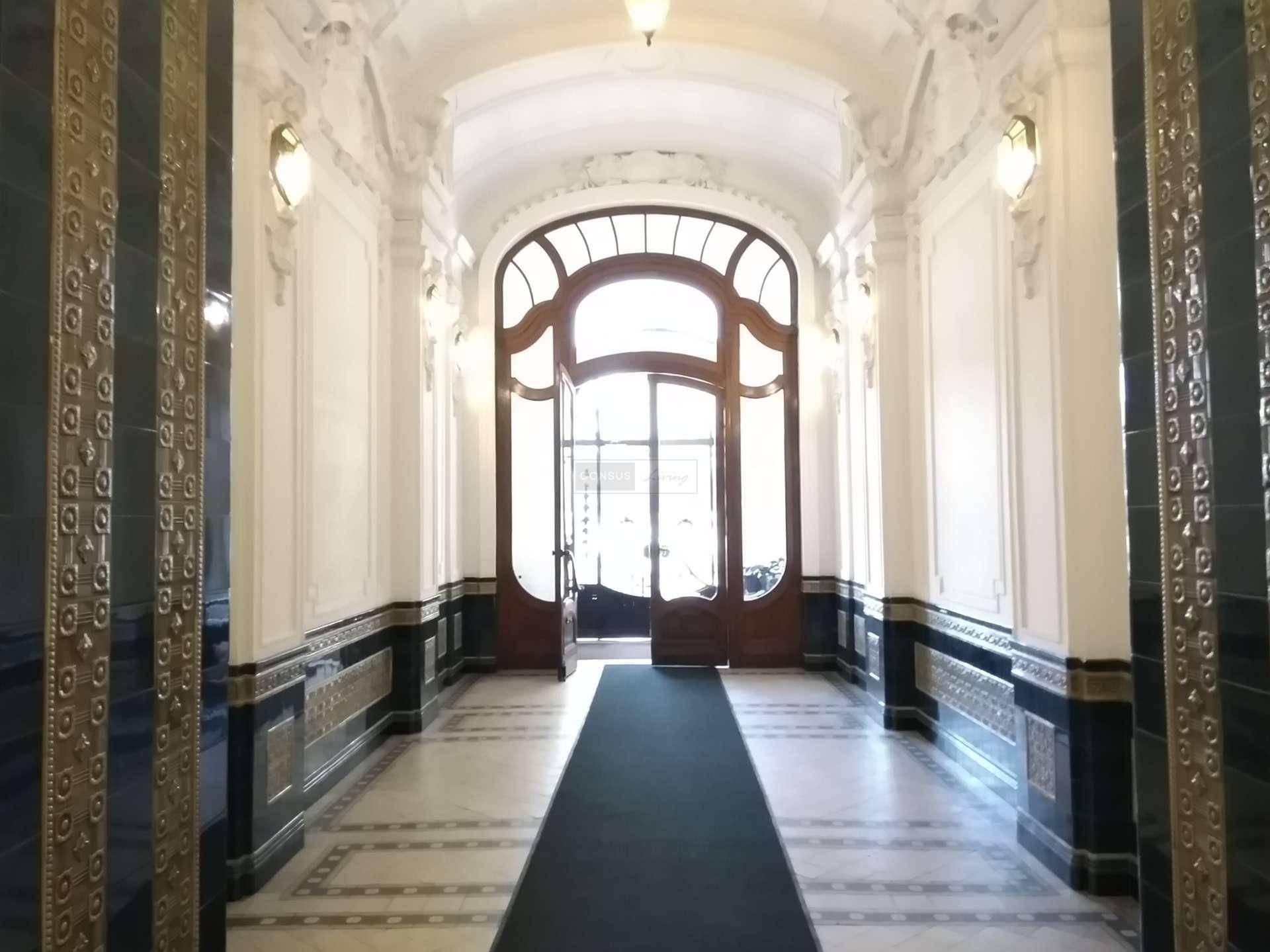 Prunkvoller Eingangsbereich mit Marmorboden, verzierten Wänden, hohen Decken und einer beeindruckenden Holztür.