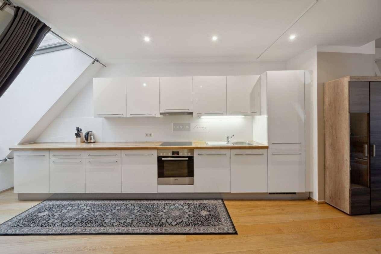 Moderne Einbauküche mit weißen Hochglanzfronten, Holzarbeitsplatte und integrierten Geräten.