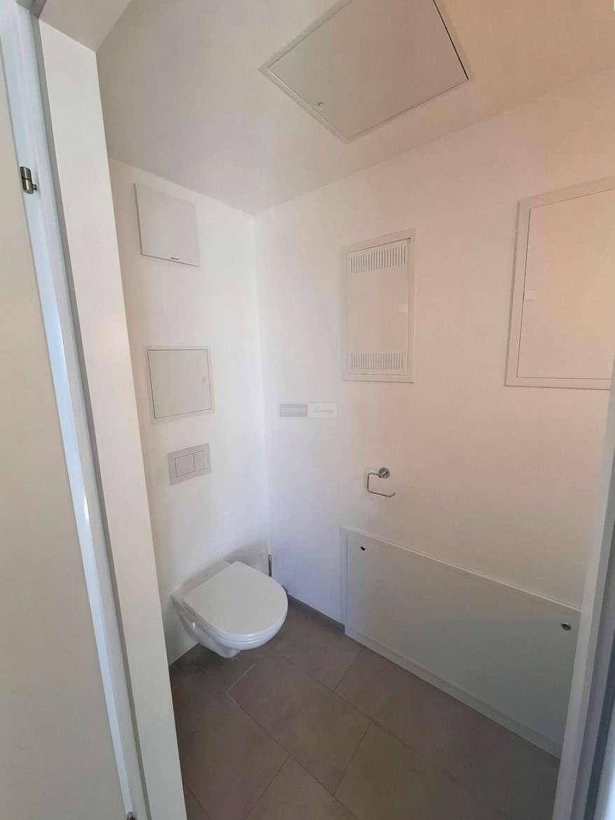 Separates Gäste-WC mit wandhängender Toilette und modernen grauen Bodenfliesen.