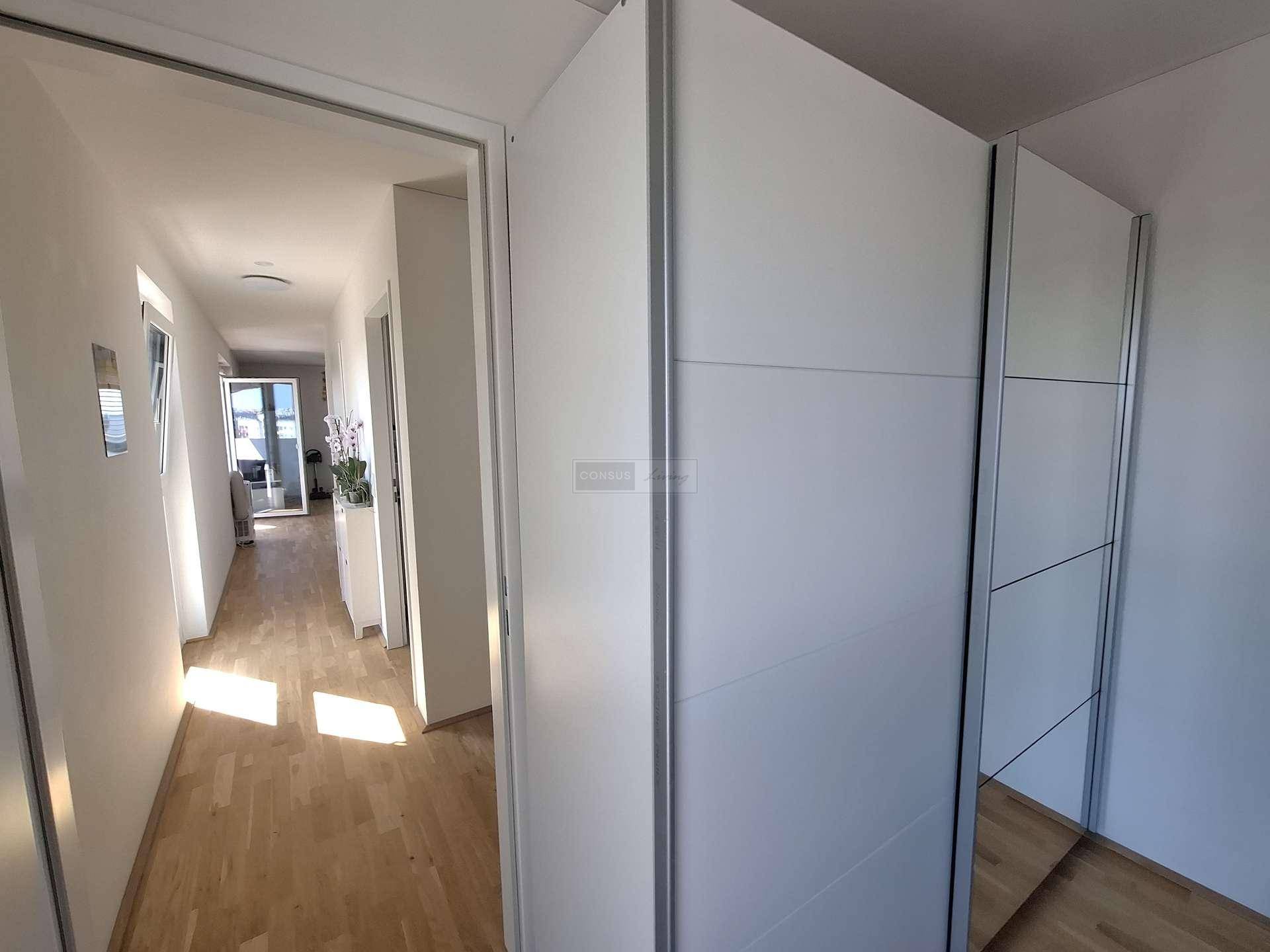 Heller Flur mit Parkettboden und praktischen Einbauschränken, der zu den weiteren Räumen führt.
