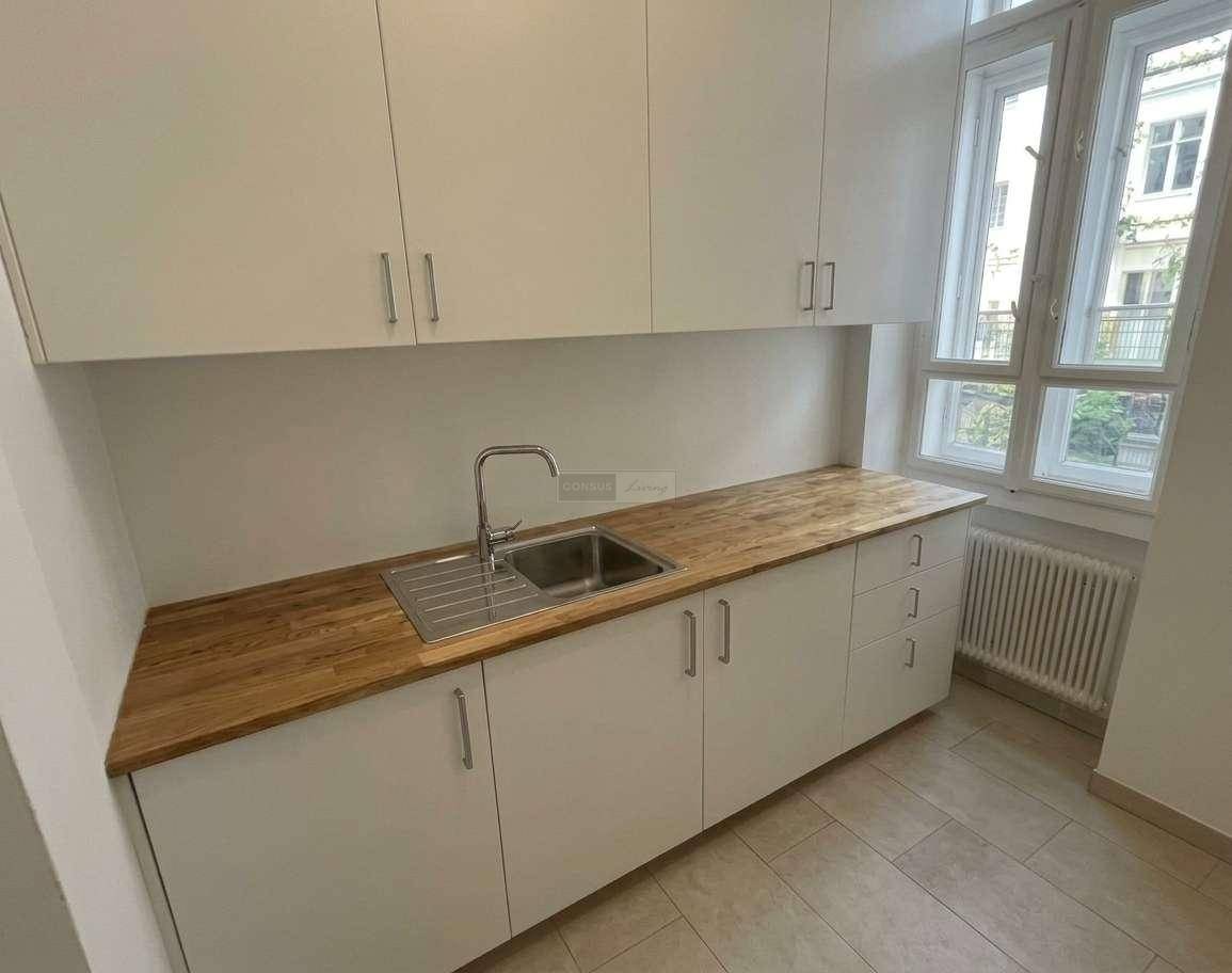 Funktionale Küche mit weißen Schränken, Holz-Arbeitsplatte, Spüle und Fenster, ideal für den täglichen Gebrauch.