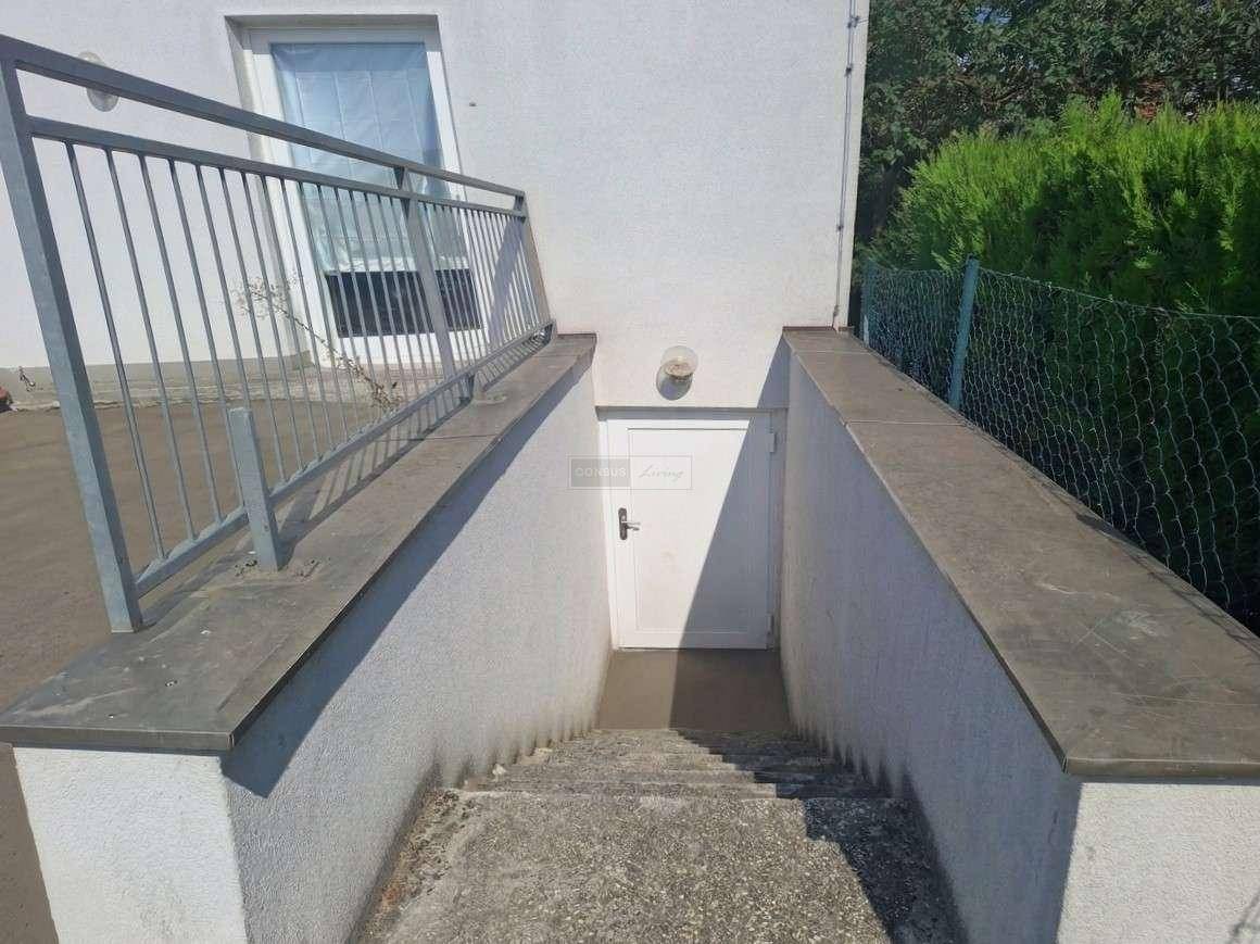 Außentreppe führt hinunter zu einem Kellereingang mit weißer Tür und Metallgeländer.