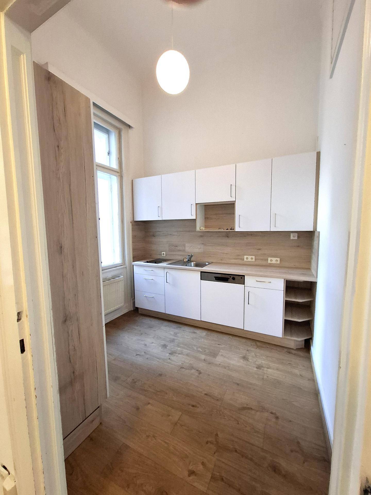 Moderne Küche mit weißen Schränken, heller Holzoptik-Arbeitsplatte und Laminatboden, ausgestattet mit Spüle und Geschirrspüler.