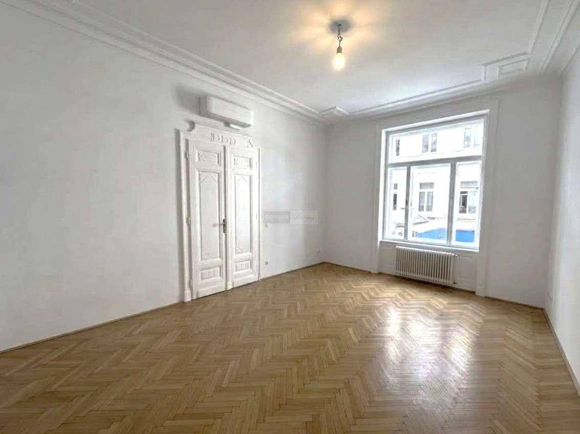 Großzügiger Raum mit elegantem Fischgrätparkett, hohen Decken, Stuck und Klimaanlage für angenehmes Wohnklima.