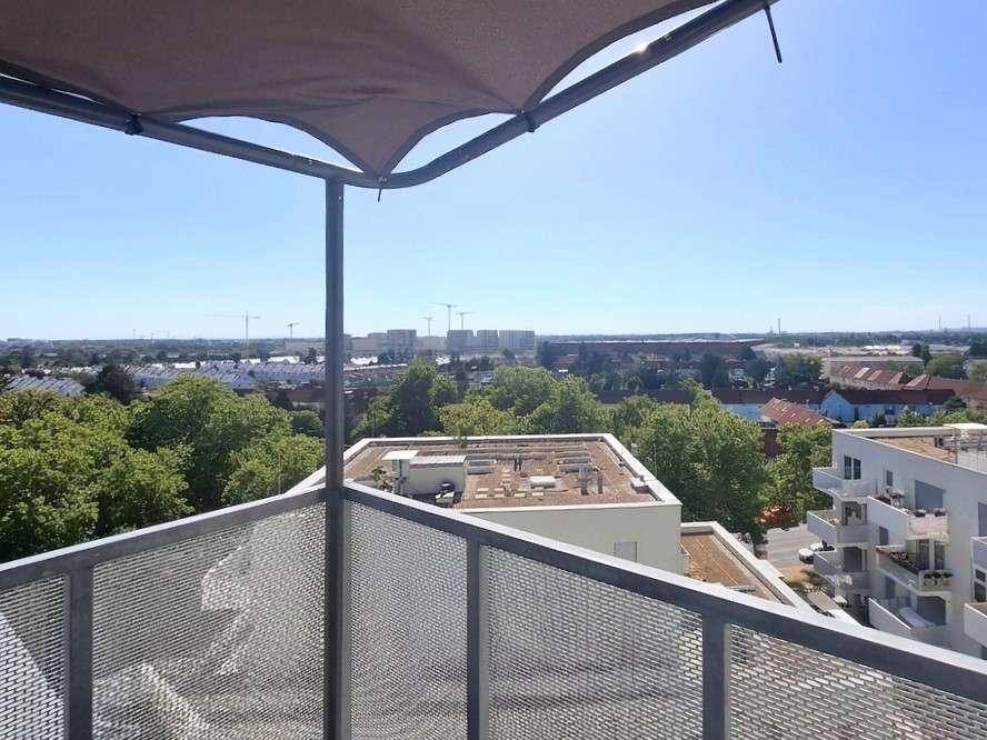 Heller Balkon mit Sonnenschutz und Panoramablick auf die Stadt und umliegende Natur.