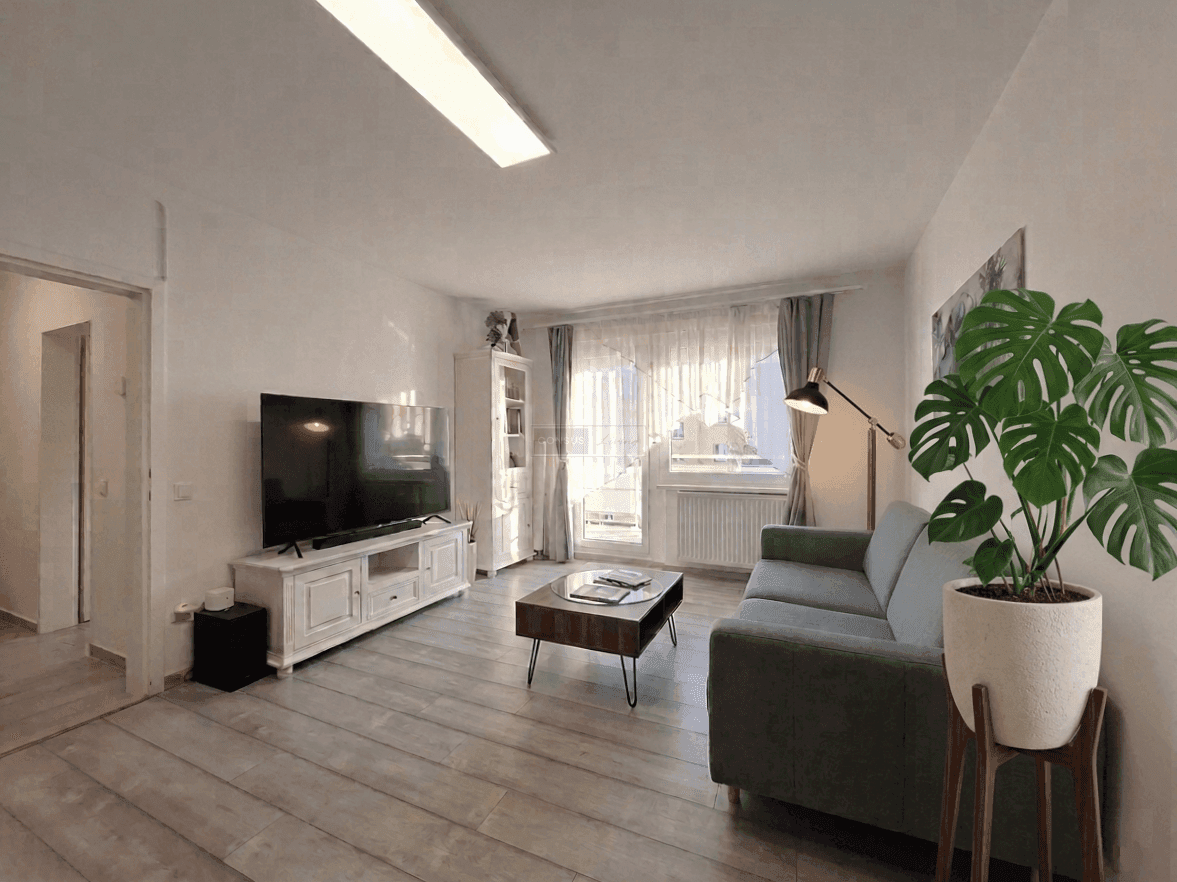Gemütliches Wohnzimmer mit modernem Sofa, Fernseher und Zugang zum Balkon.