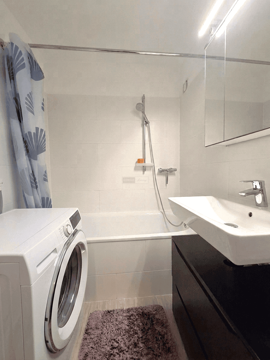 Modernes Badezimmer mit Badewanne, Waschbecken, Spiegelschrank und Waschmaschine.