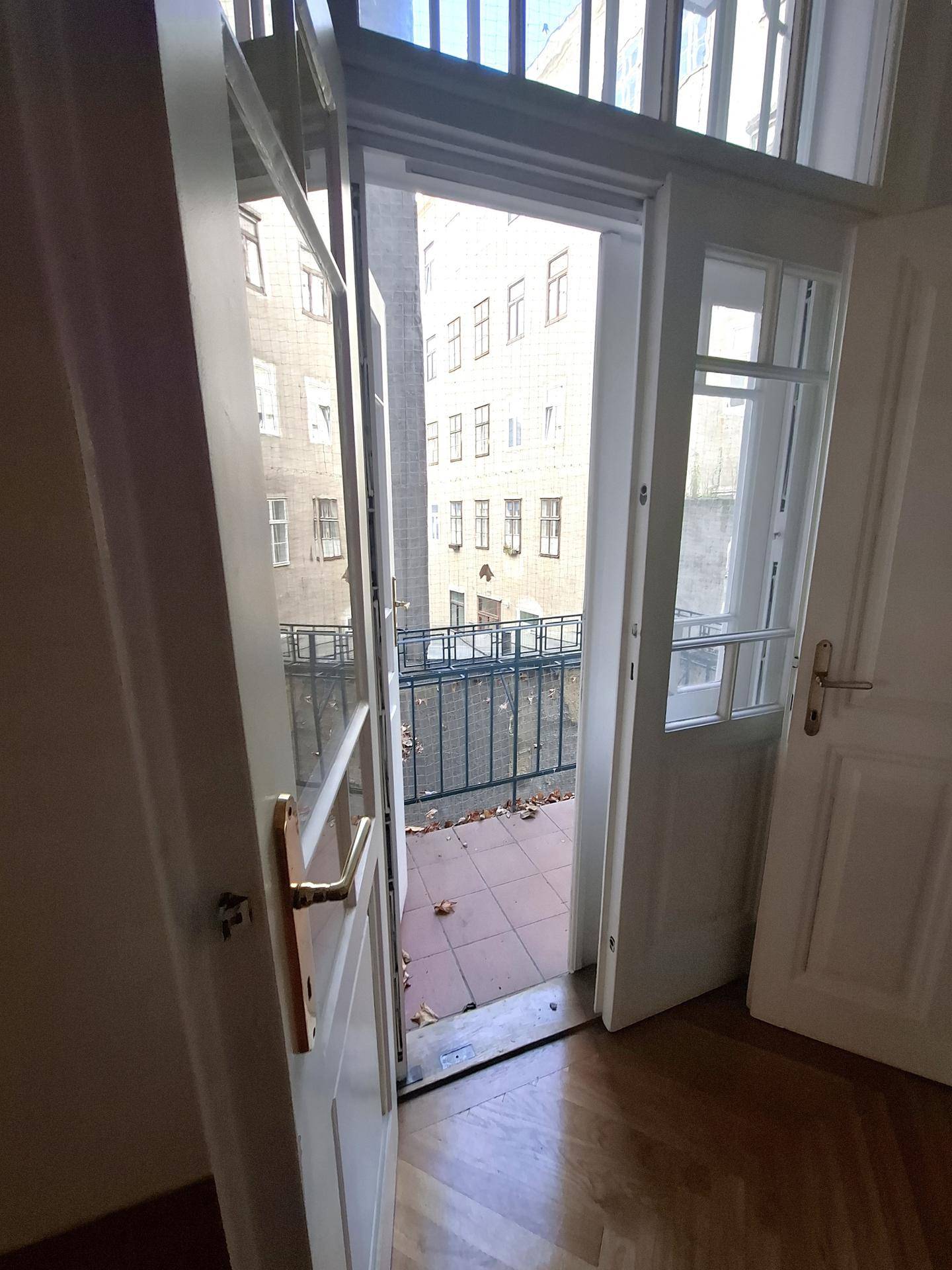 Kleiner Balkon mit Fliesenboden und Blick auf die umliegenden Gebäude der Stadt.