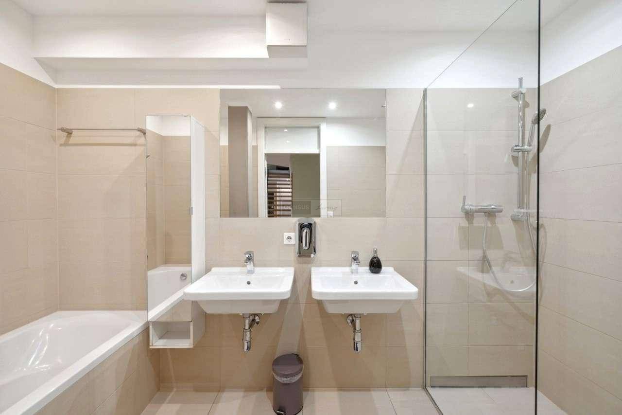 Modernes Badezimmer mit Doppelwaschbecken, Badewanne und begehbarer Dusche mit Glaswand.