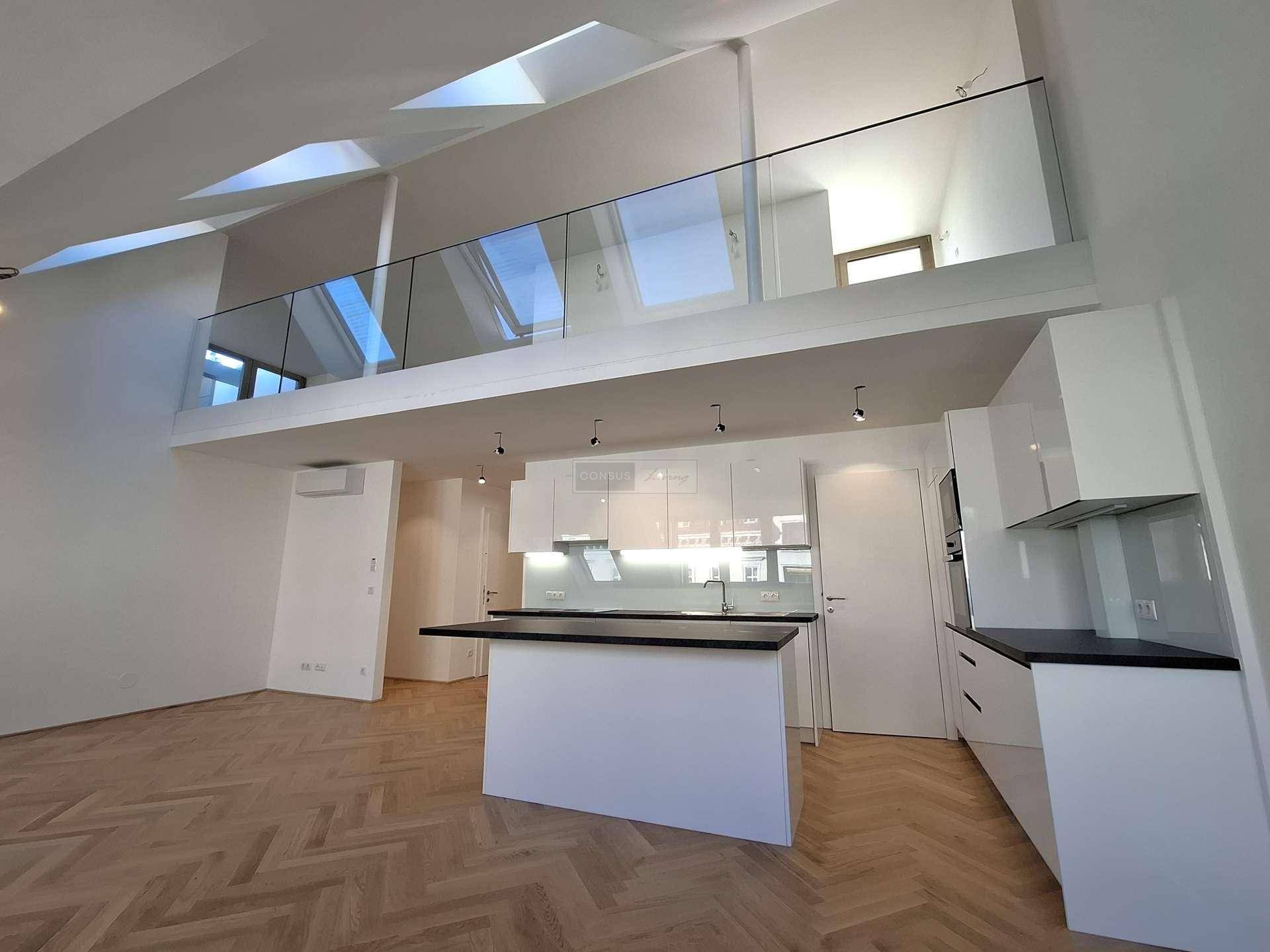 Offene Küche mit weißer Einrichtung und Blick auf die Galerie mit Glasgeländer.