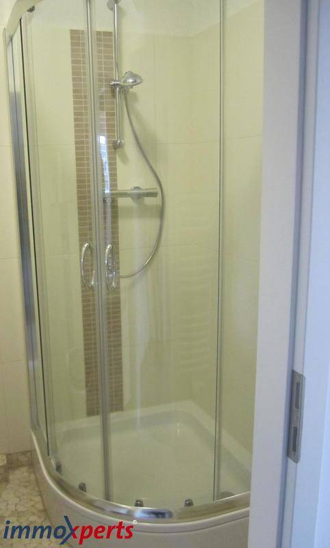 Moderne Duschkabine mit Glastüren und hellen Fliesen im Badezimmer.