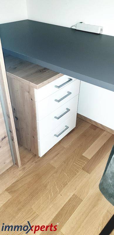 Detailansicht eines Schreibtisches mit Schubladenelement und Holzboden, funktional und stilvoll.