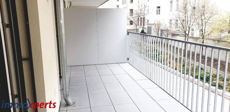 Heller Balkon mit Fliesenboden und Blick auf den Innenhof, ideal zum Entspannen.