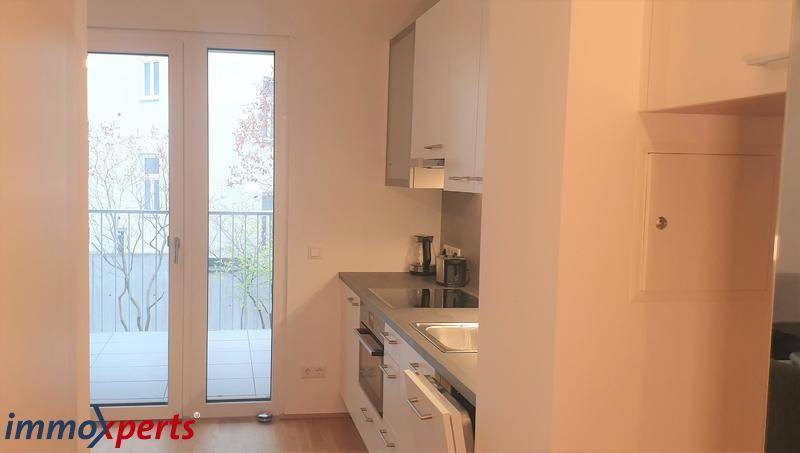 Kleine Küchenzeile mit modernen Geräten und Zugang zu einem französischen Balkon.