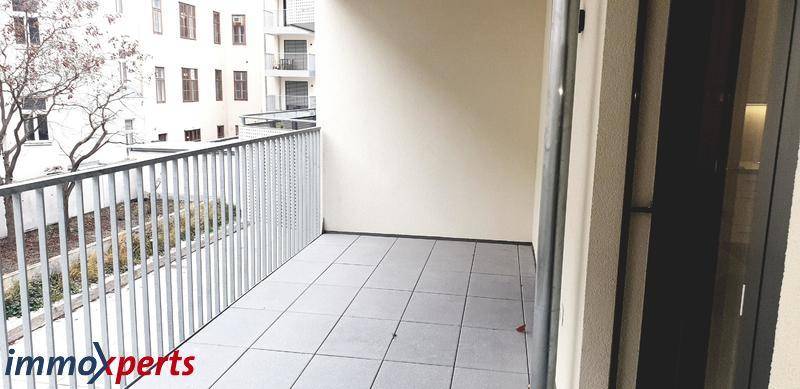 Langer Balkon mit Fliesenboden und Metallgeländer, bietet viel Platz im Freien.