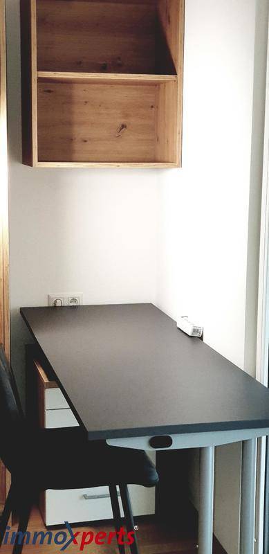 Arbeitsbereich mit Schreibtisch und Regal in einem hellen Schlafzimmer, ideal für Homeoffice.