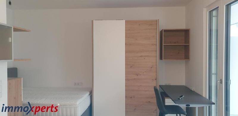 Schlafzimmer mit Bett, Kleiderschrank und Schreibtisch in modernem Design, gut organisiert.