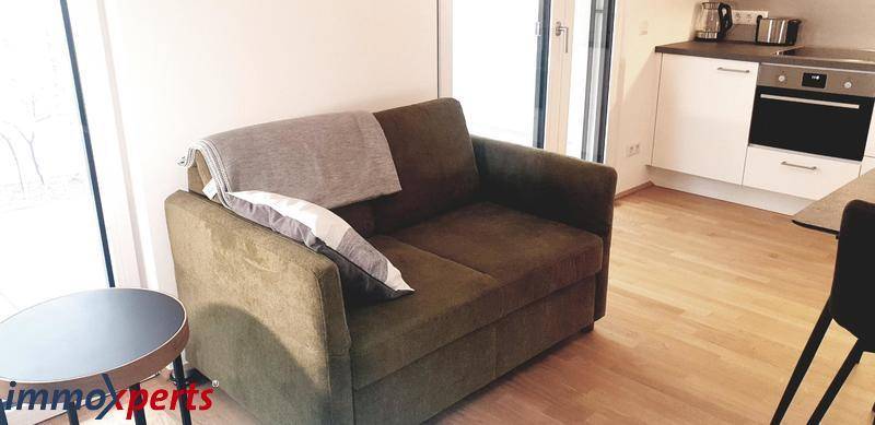 Gemütlicher Wohnbereich mit Sofa und Zugang zu einem französischen Balkon, hell und einladend.